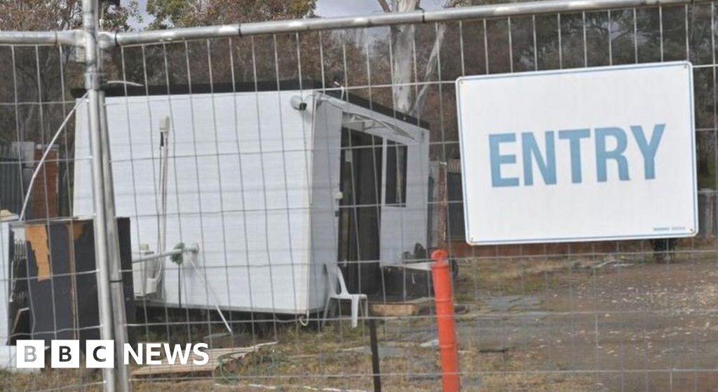 A Russian diplomat squats near the Australian Parliament in the embassy recruitment queue

