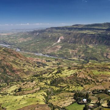 An overhead view of the East African Rift, with a river in a cultivated valley flanked by steep cliffs