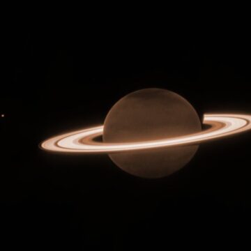 saturn, its rings and three moons stand out against the blackness of space in this james webb space telescope photo